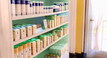 Shelves stocked with various skincare and beauty products near a sunlit door.