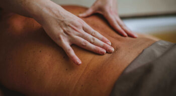 Close-up of hands giving a back massage to a person lying face down on a massage table.