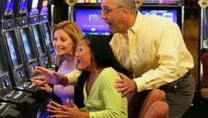 Friends cheer a woman on as she wins on a slot machine.